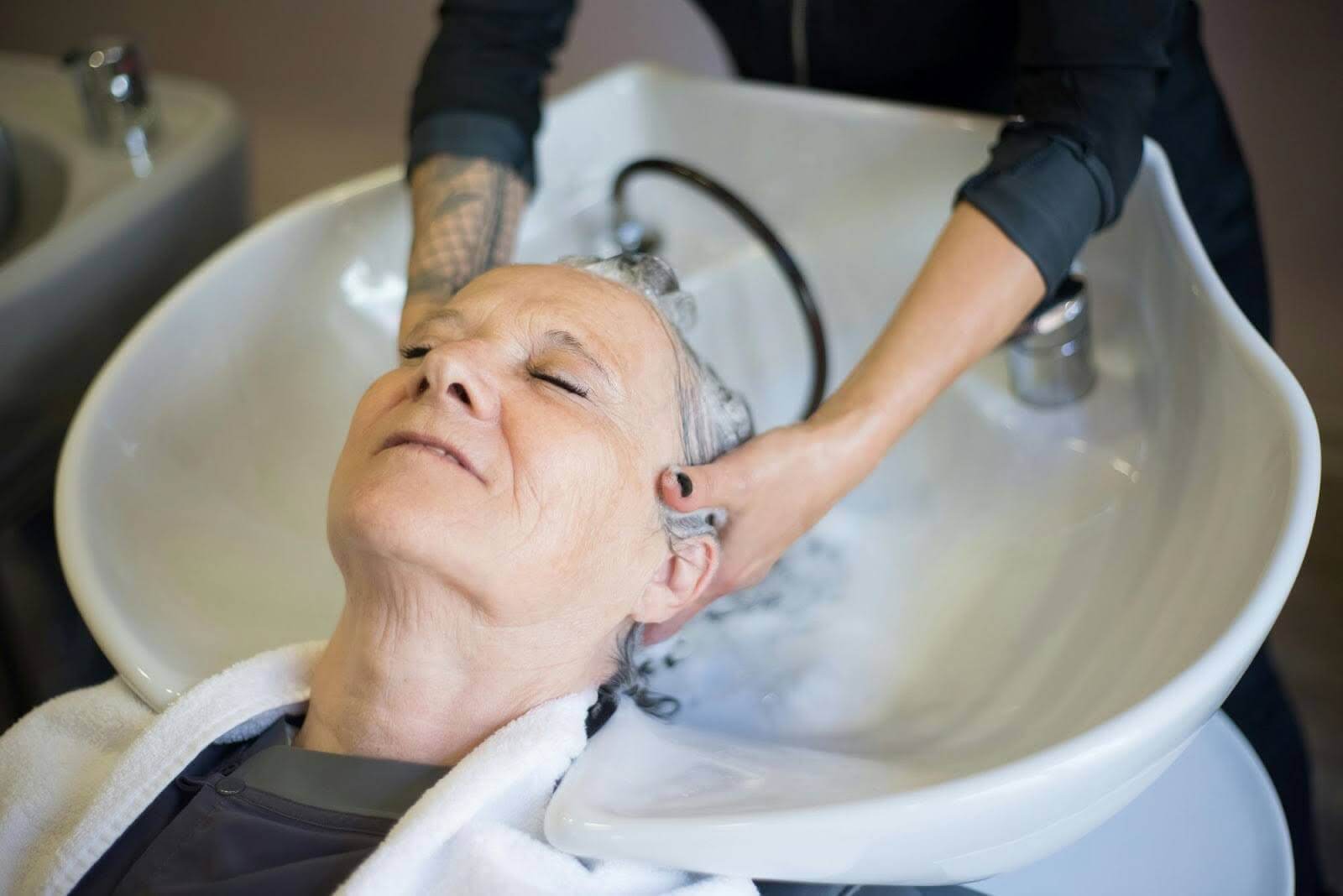 A woman getting her hair shampooed in a hair salon.