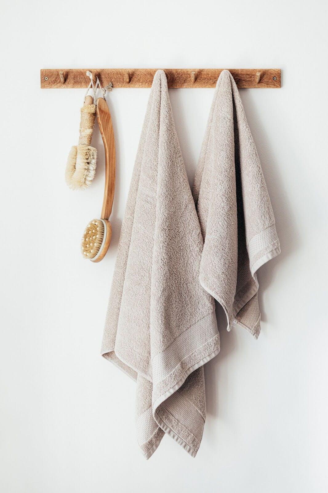 Two towels and cleaning supplies hung up on a wall. Two towels and cleaning supplies hung up on a wall.